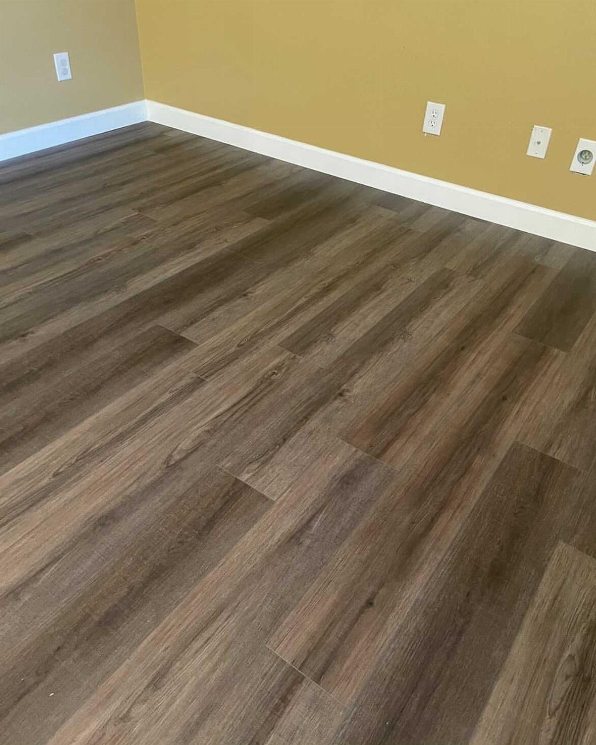 20 mil LVP Flooring: 6 Install Ideas for Home & Commercial Spaces 5 Dark brown wood-look luxury vinyl plank flooring installed in a room with yellow walls.