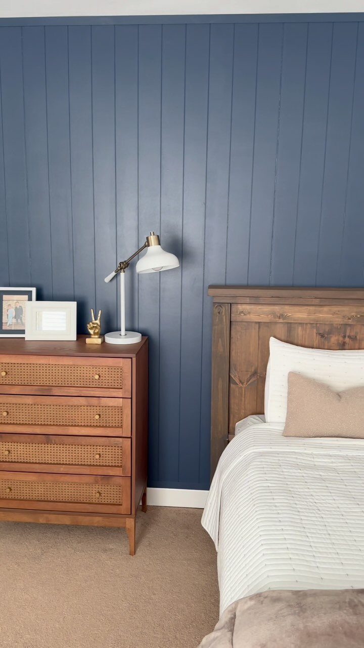 10 Accent Wall Panels for Every Room Style 2 Dark blue vertical wood paneling serves as an accent wall behind a wooden dresser and bed.