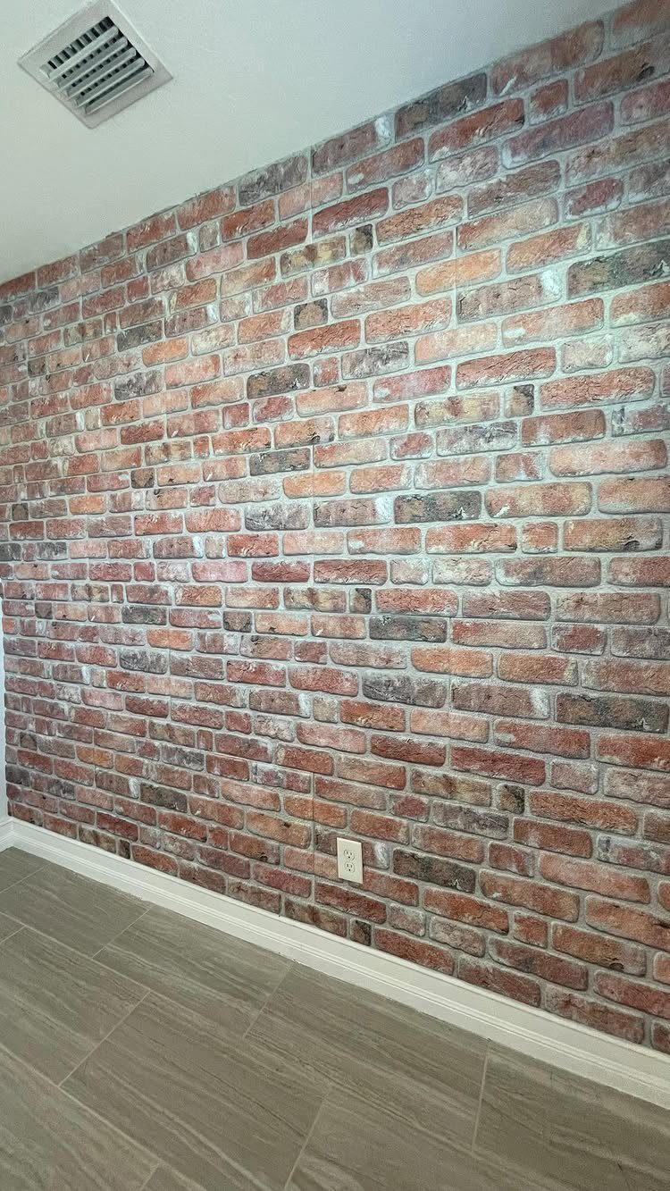 10 Accent Wall Panels for Every Room Style 9 Red and brown brick patterned accent wall panels installed above a grey wood floor.