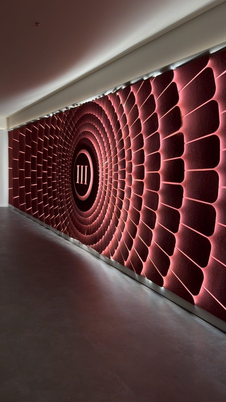 Red textured acoustic wall panels arranged in a large concentric circular pattern with integrated lighting.