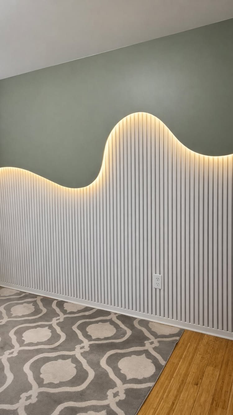 White vertical slat wood paneling with wavy LED backlighting on a sage green wall.