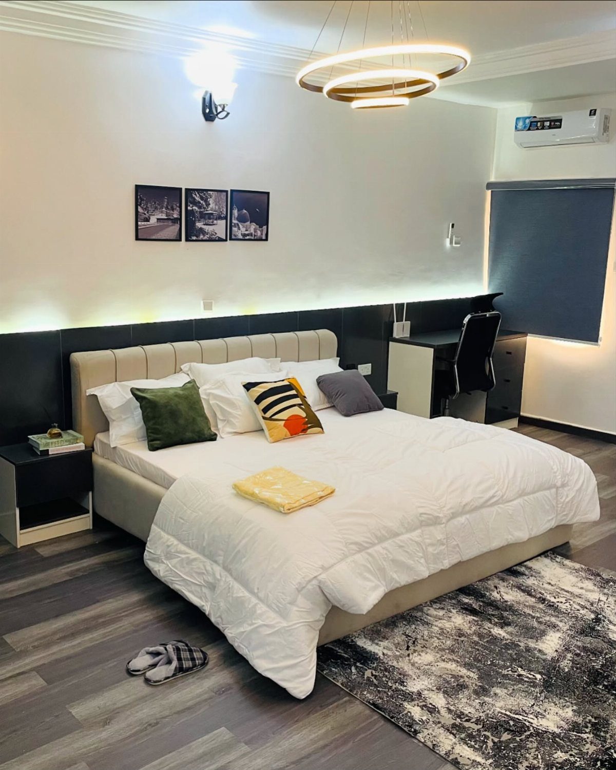 Affordable Wood Flooring: 6 Styles That Look Expensive 4 Modern bedroom with a large white bed and grey wood-look plank flooring.