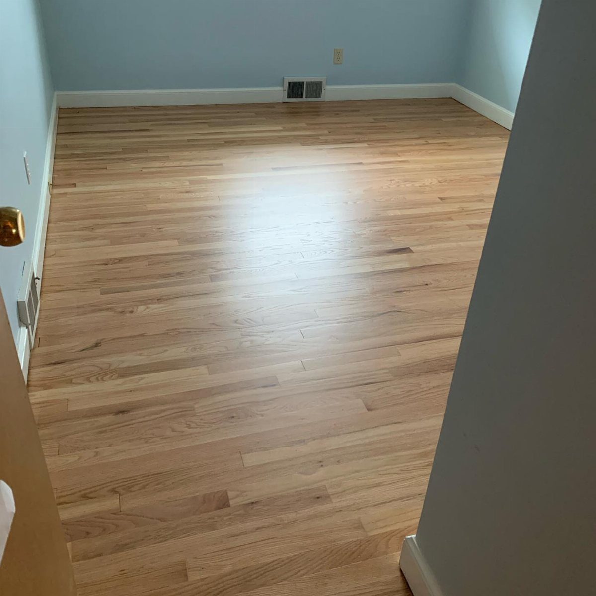 Affordable Wood Flooring: 6 Styles That Look Expensive 5 Light-colored hardwood flooring installed in an empty room with pale blue walls.