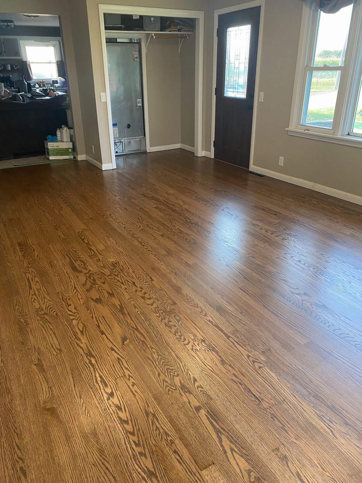 Affordable Wood Flooring: 6 Styles That Look Expensive 6 Polished medium-toned wood flooring installed in a room with grey walls and a dark door.