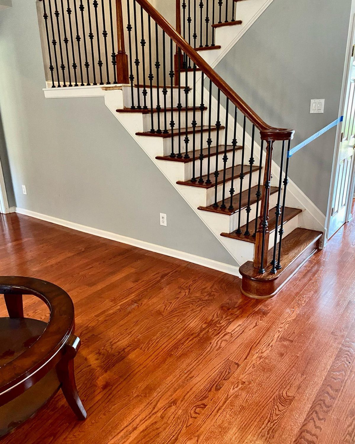 Affordable Wood Flooring: 6 Styles That Look Expensive 1 Red oak hardwood flooring with a warm finish in a room next to a staircase.