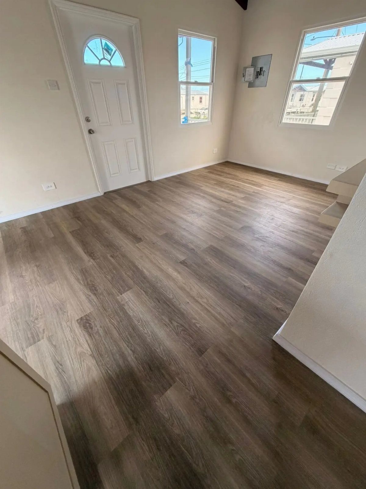 Affordable Wood Flooring: 6 Styles That Look Expensive 2 Wood-look plank flooring installed in an empty room with white walls and a white door.