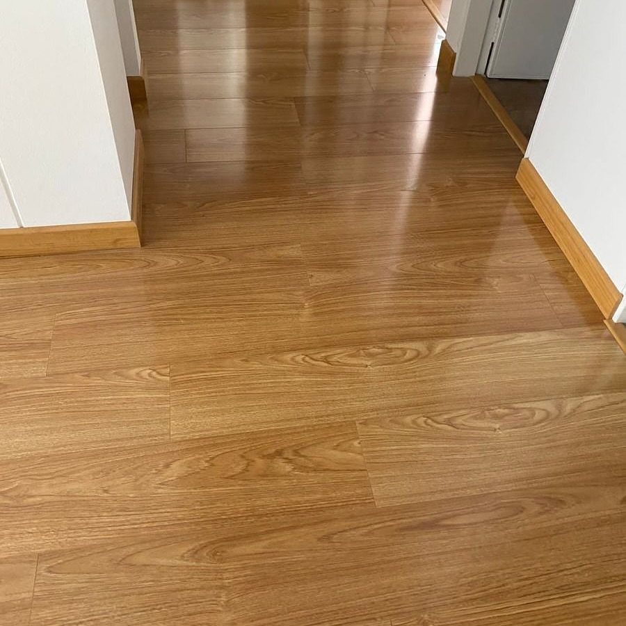 Affordable Wood Flooring: 6 Styles That Look Expensive 3 Polished light brown wood-grain laminate flooring stretching through a hallway with white walls.
