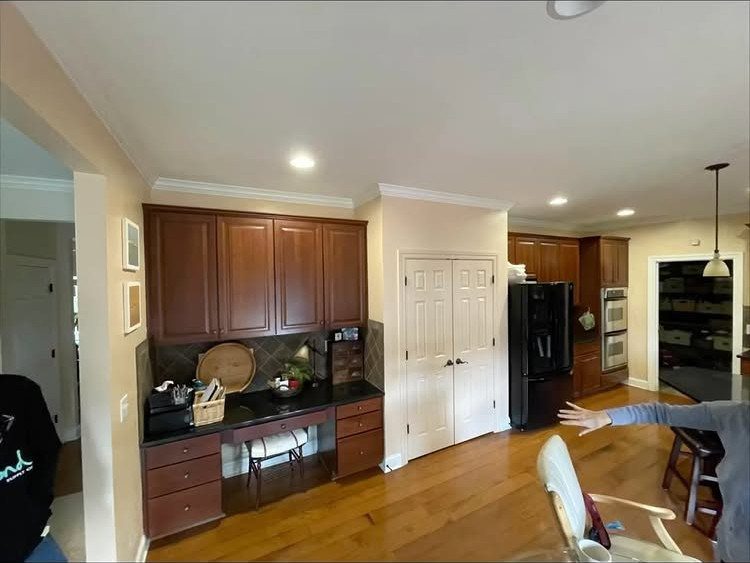 Warm wooden floors stretching through a kitchen with dark wood cabinetry and white doors.