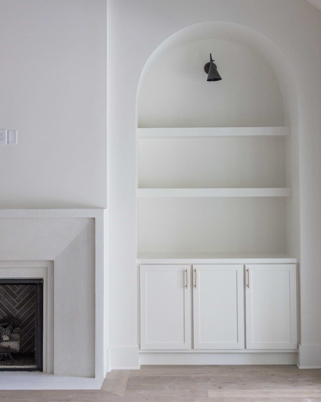 17 Built-In Shelves Living Room Ideas That Balance Style and Storage 13 White built-in shelving unit with an arched alcove and lower cabinets against a white wall.