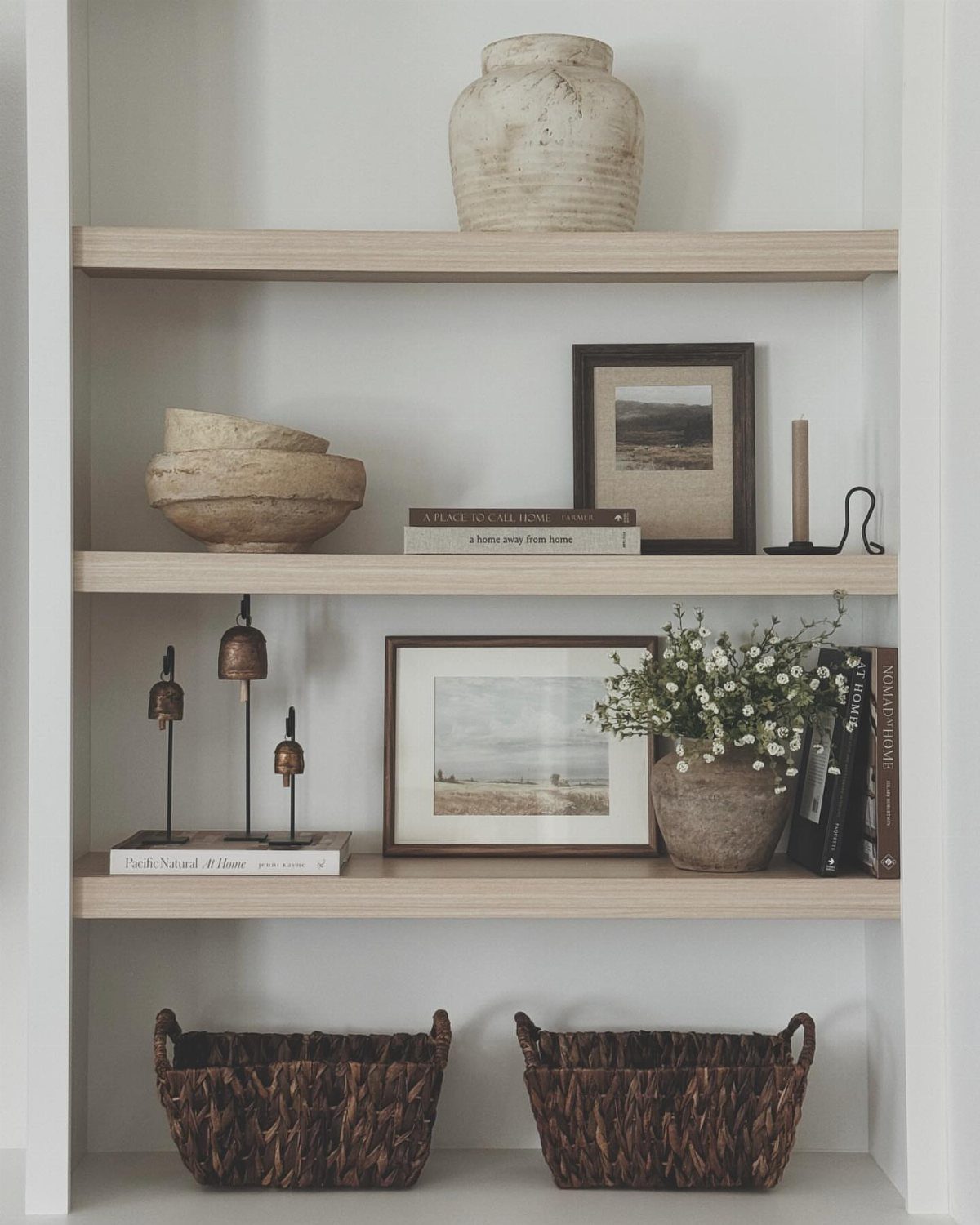 17 Built-In Shelves Living Room Ideas That Balance Style and Storage 1 Light wood built-in shelves decorated with ceramic vases, framed art, books, and small plants.