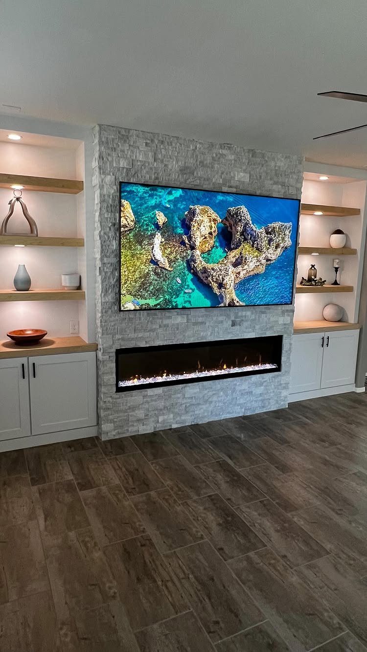 17 Built-In Shelves Living Room Ideas That Balance Style and Storage 8 Grey stone feature wall with a large television and a linear electric fireplace below.
