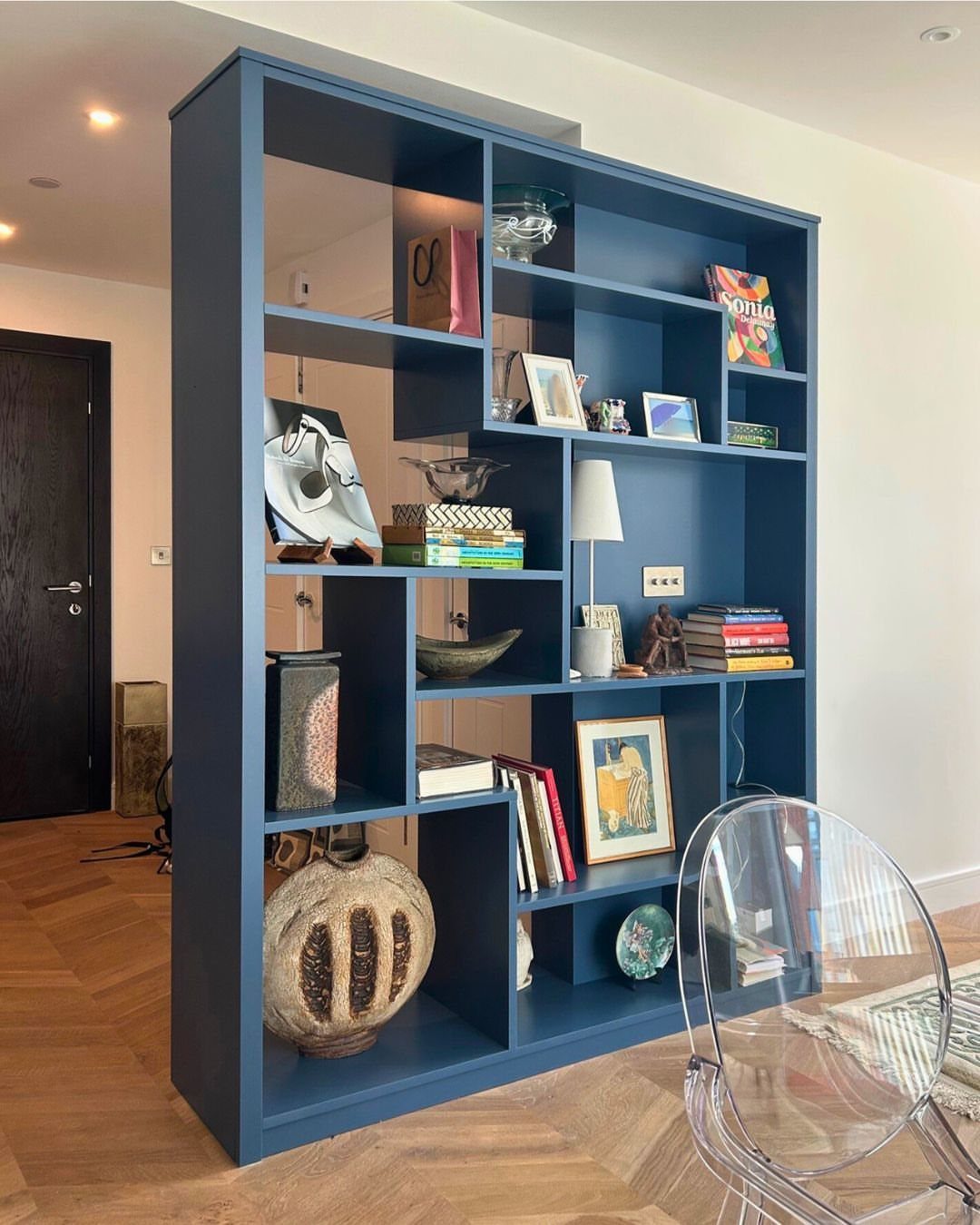 17 Built-In Shelves Living Room Ideas That Balance Style and Storage 17 Navy blue built-in shelving unit filled with books and decor in a living room.