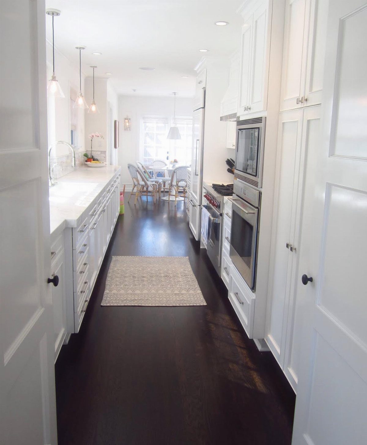 Dark Wood Floors with Light Wood Cabinets: 10 Kitchen Pairings 8 White kitchen cabinets and countertops set against dark hardwood flooring in a bright room.
