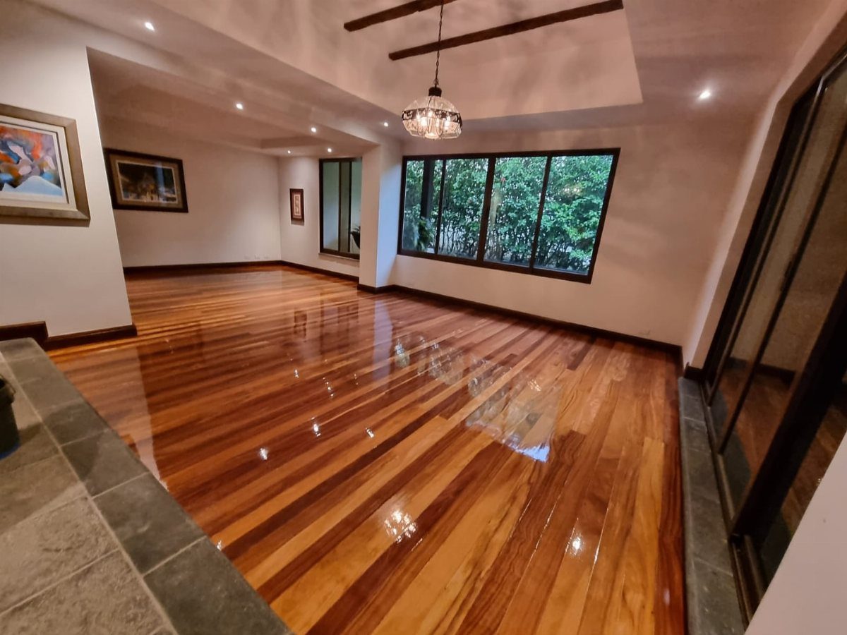 Fancy Wood Floors: 8 Ideas for Rich, Character-Filled Spaces 8 Polished reddish-brown hardwood floors reflecting light in a spacious, modern room with large windows.