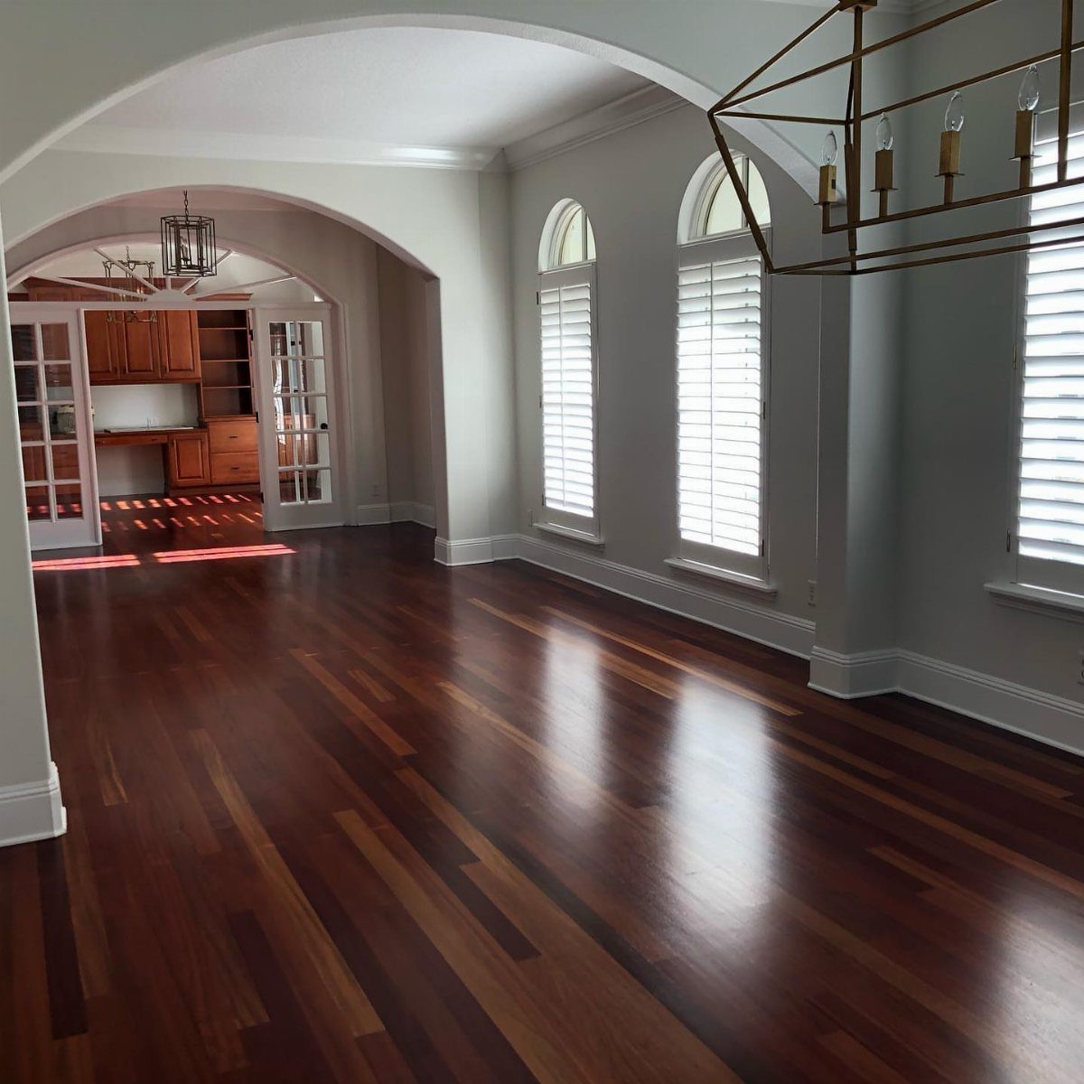 Floor and Wall Color Combinations: 27 Rooms That Get It Right 25 Dark hardwood floors and light grey walls in a room with arched windows and shutters.