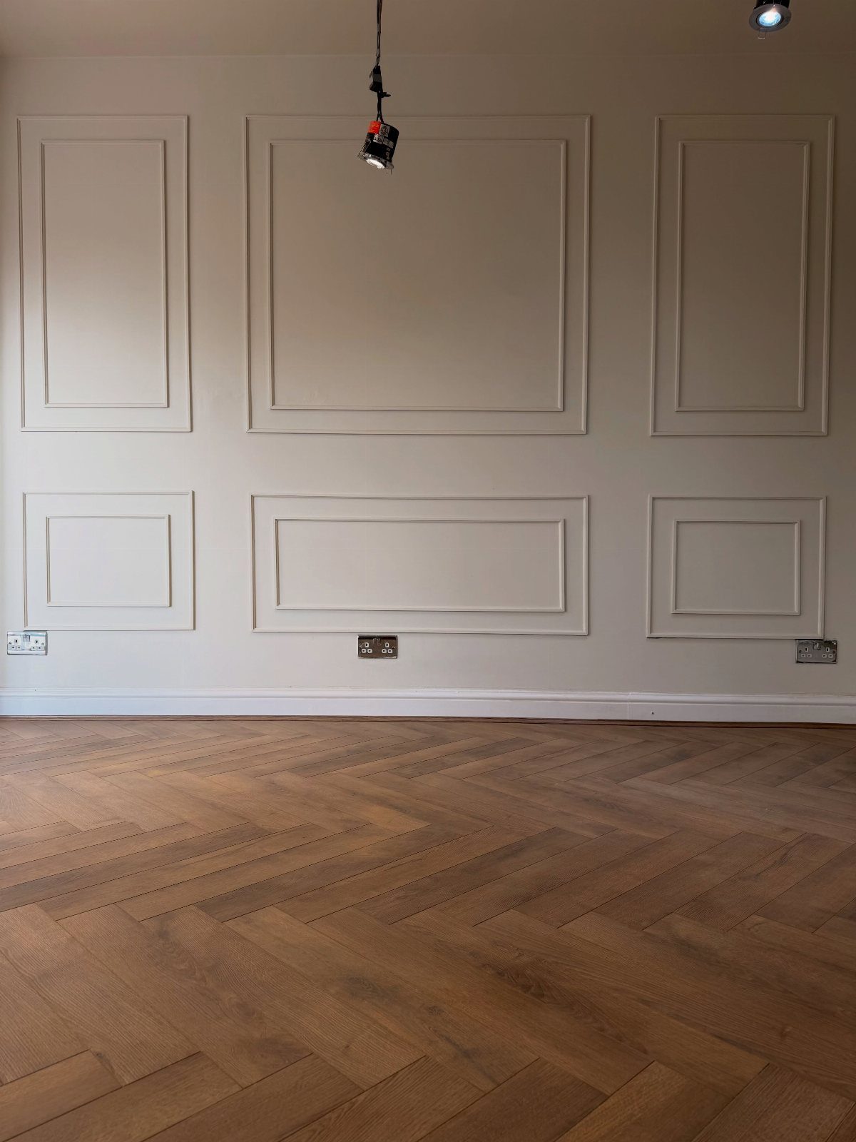 Floor and Wall Color Combinations: 27 Rooms That Get It Right 19 Herringbone wood flooring meets light beige paneled walls with decorative molding in an empty room.