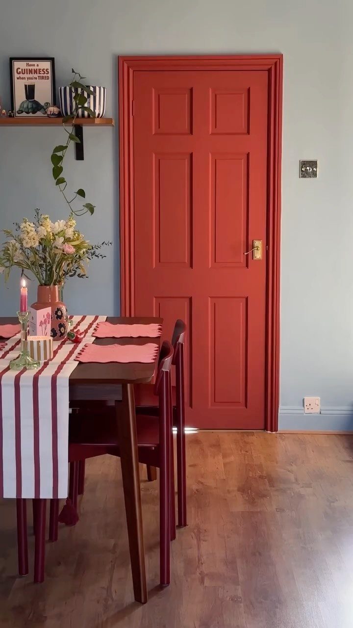Floor and Wall Color Combinations: 27 Rooms That Get It Right 5 Red paneled door against light blue walls in a dining room with wooden furniture.