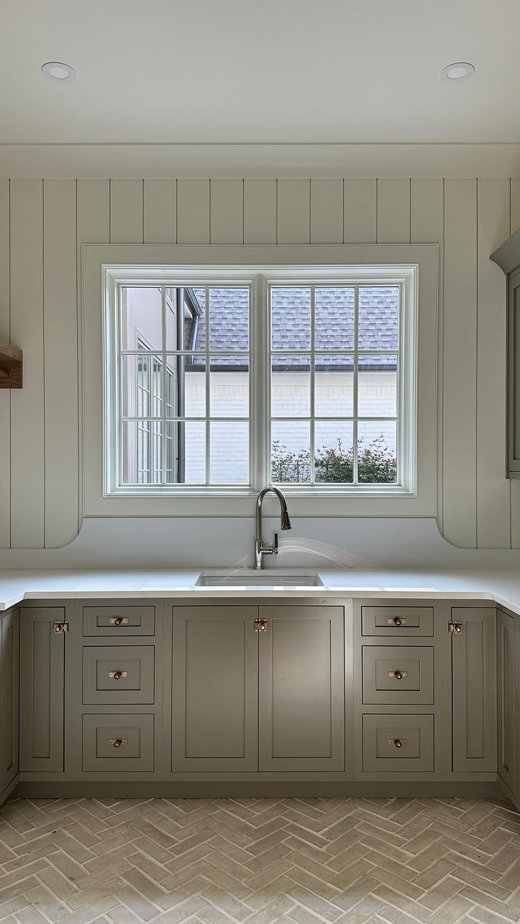 Floor Tile for Laundry Room: 11 Styles That Hold Up to Real Life 9 Herringbone pattern floor tiles in a laundry room with grey cabinets and a white sink countertop.