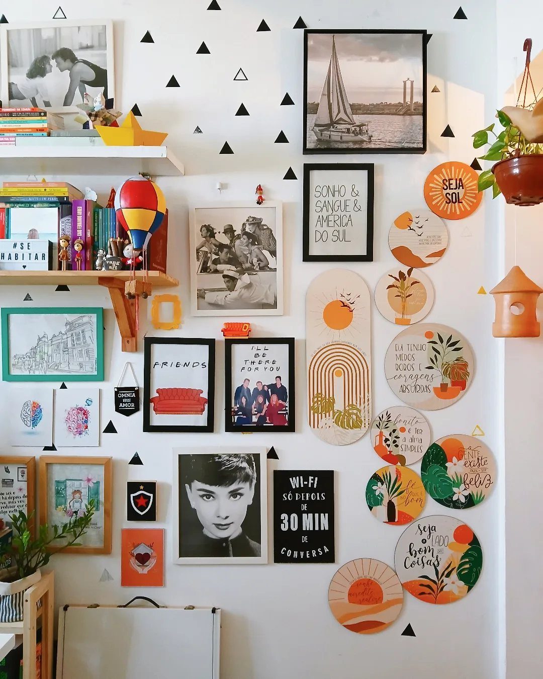10 Interior Walls Ideas for 2026: Colors, Textures & Clever Details 9 A white wall decorated with framed photos, circular art, and small black triangle decals.