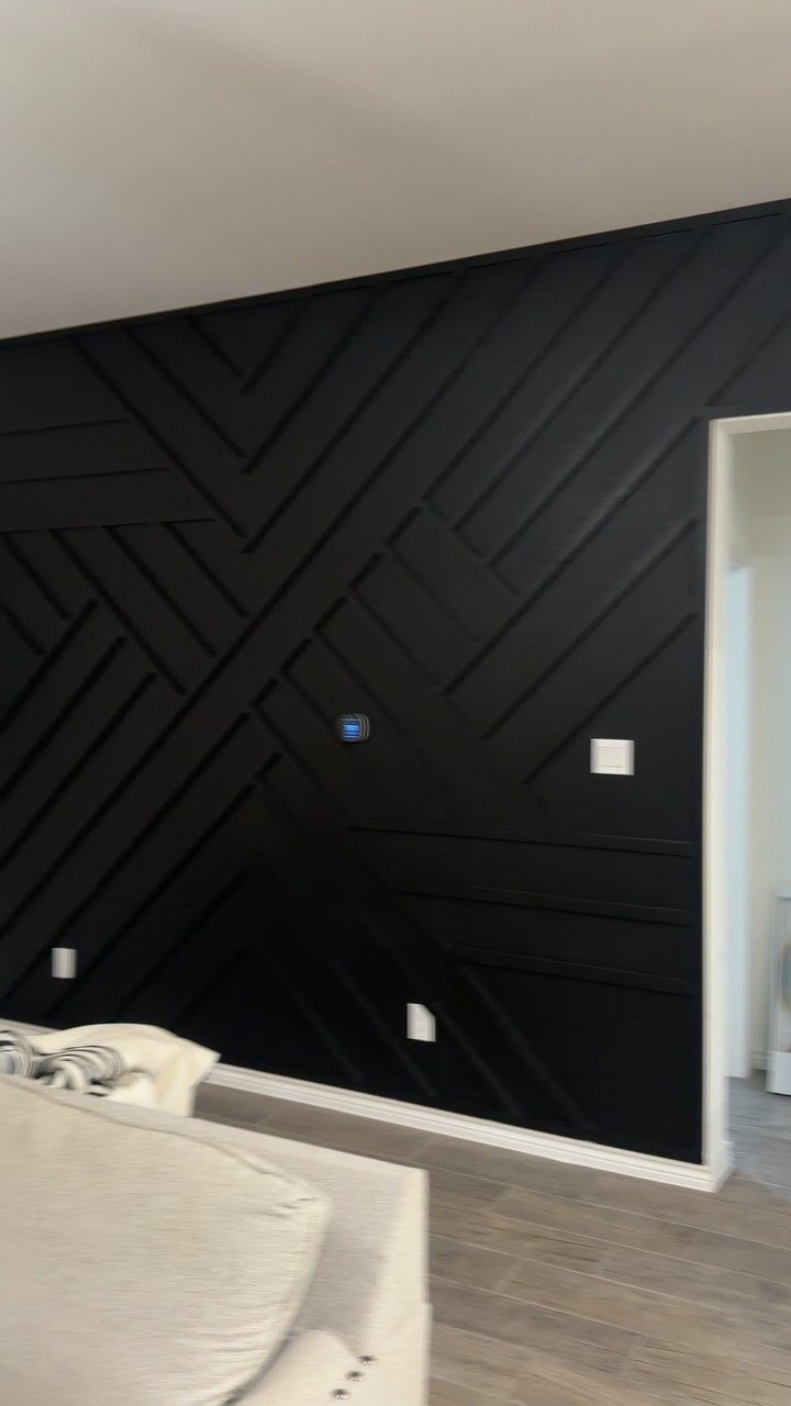 10 Interior Walls Ideas for 2026: Colors, Textures & Clever Details 5 Black geometric accent wall with raised wooden slats in a modern living room setting.
