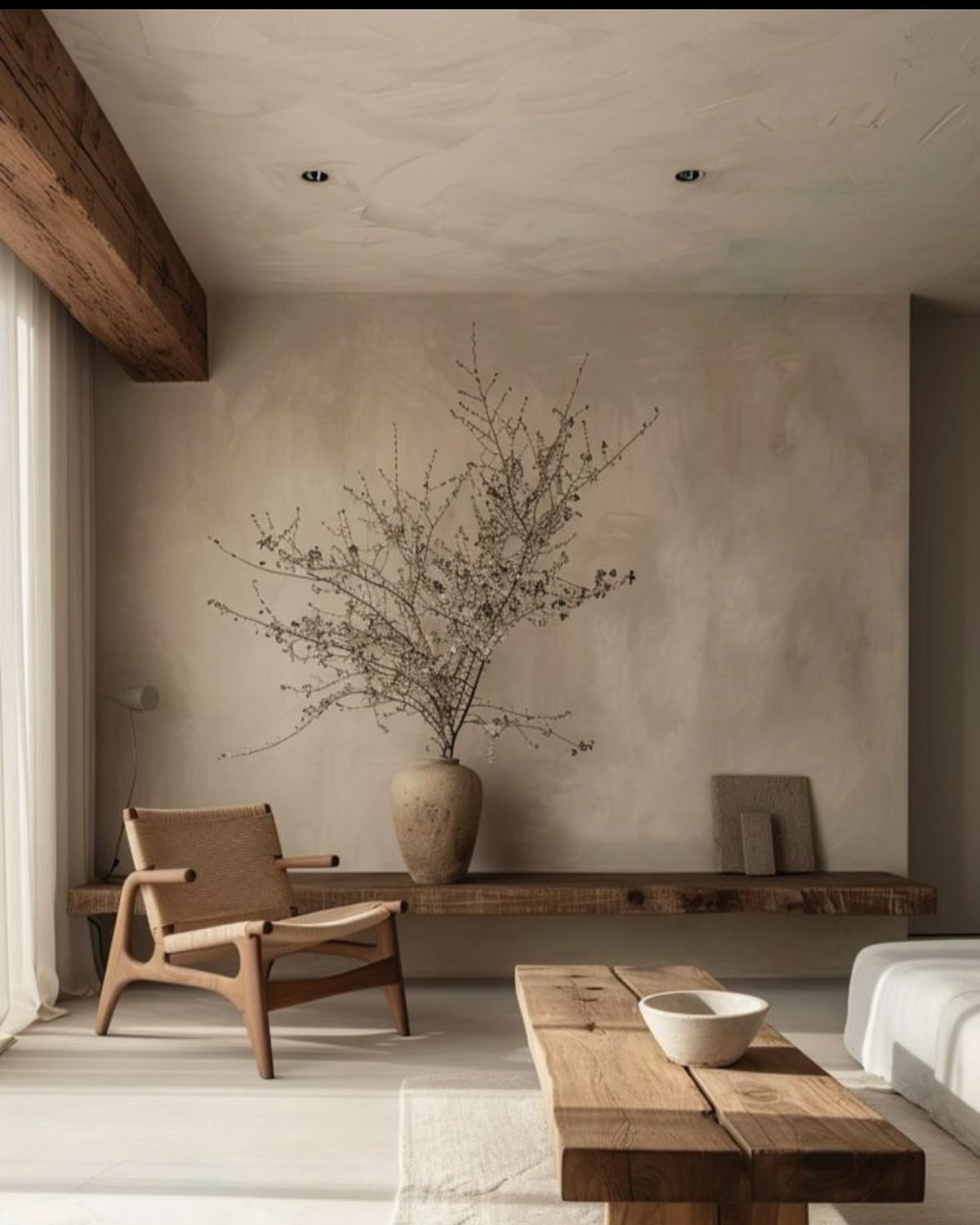 10 Interior Walls Ideas for 2026: Colors, Textures & Clever Details 3 A textured beige limewash wall in a minimalist room with wooden furniture and dried branches.