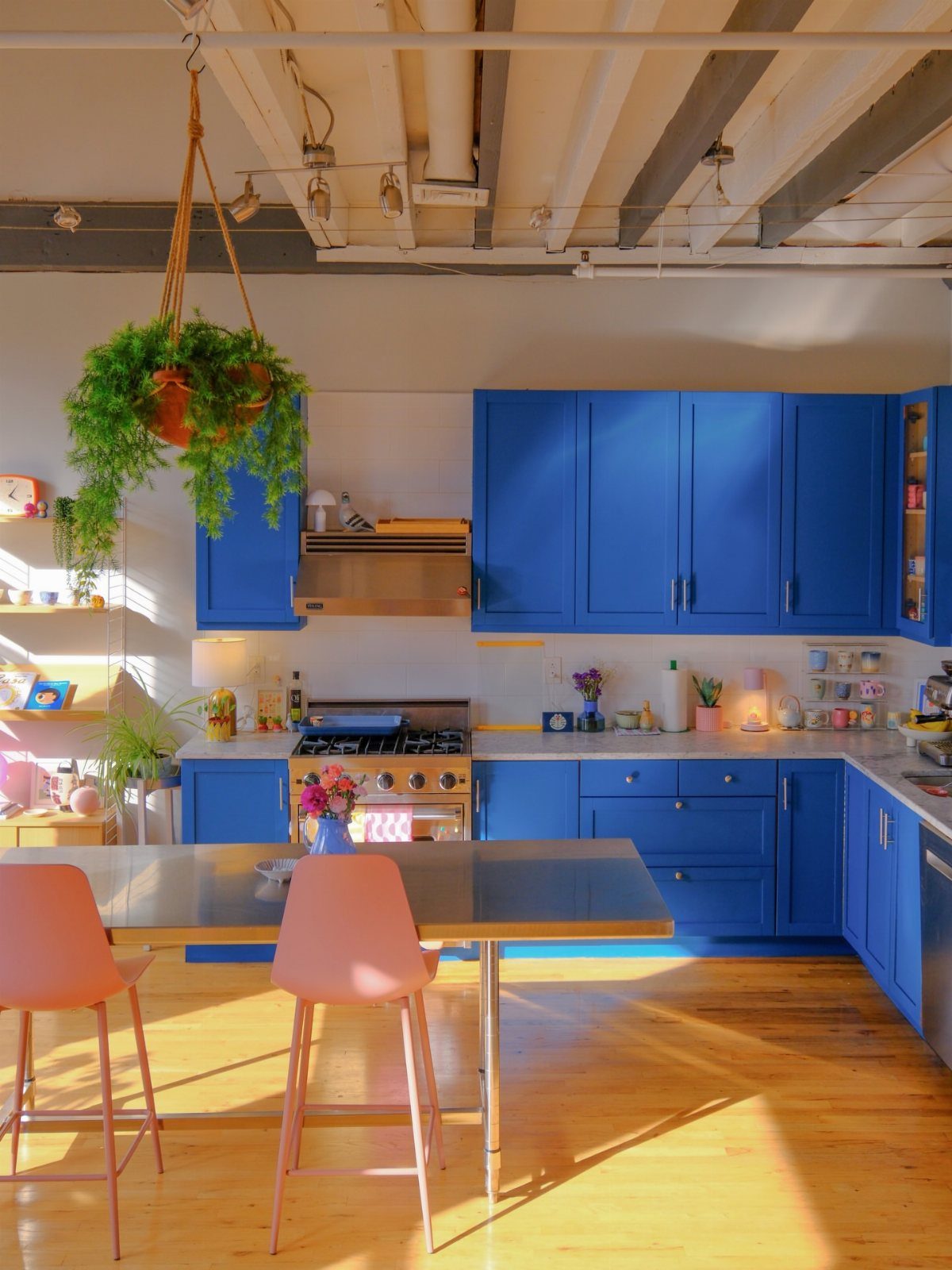 Kitchen Floors with Wood Cabinets: 10 Ideas That Work 4 Blue kitchen cabinets and light wood flooring illuminated by bright sunlight in a modern kitchen.