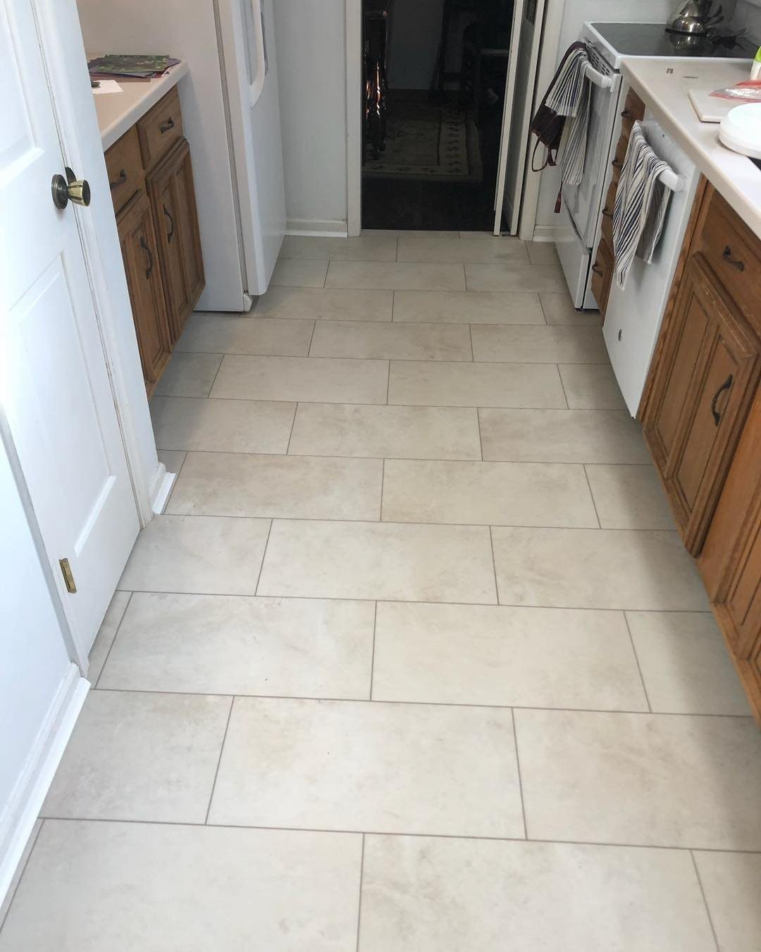 Kitchen Floors with Wood Cabinets: 10 Ideas That Work 9 Light beige rectangular floor tiles in a kitchen with wooden cabinets and white appliances.