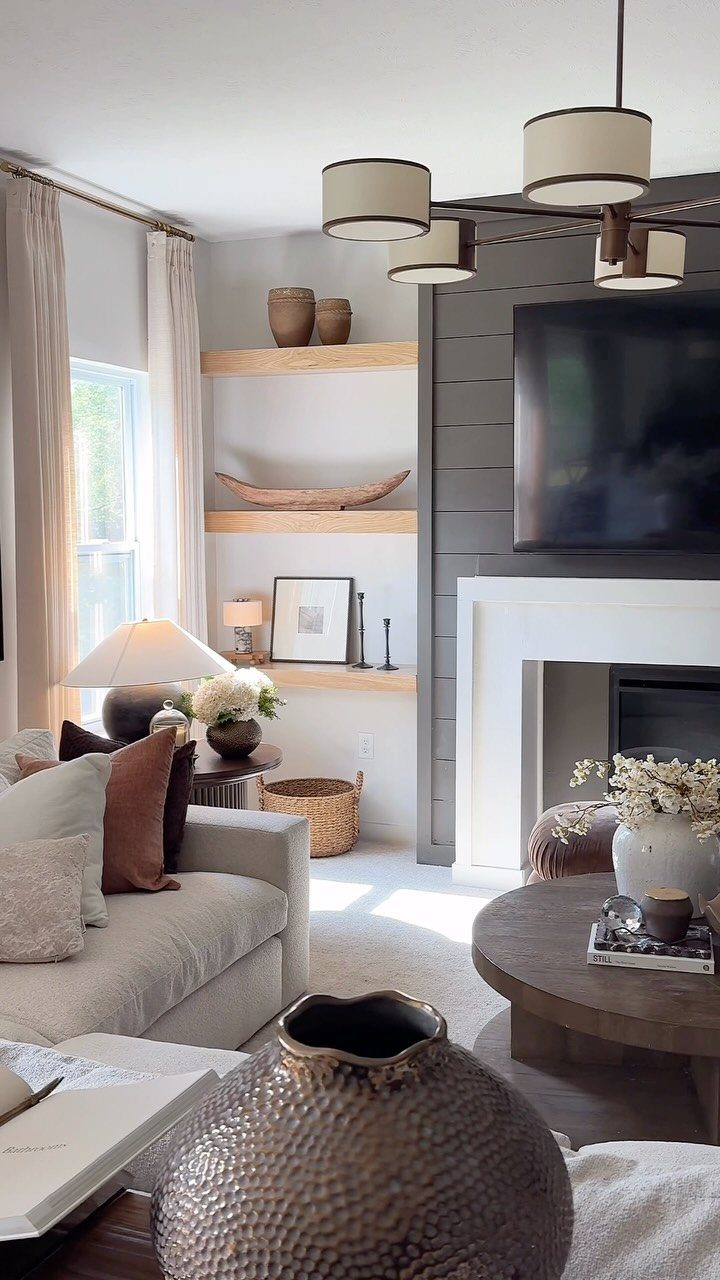 A living room featuring a television mounted on a dark grey shiplap wall above a white fireplace.