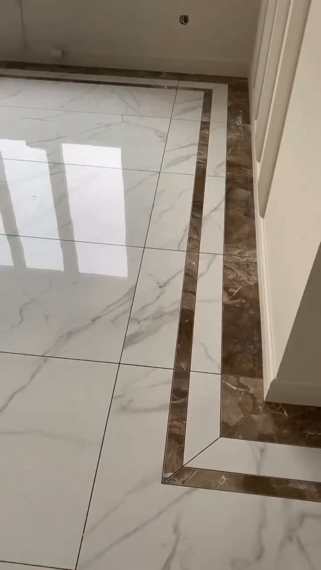 White marble floor tiles with a decorative dark brown marble border pattern.