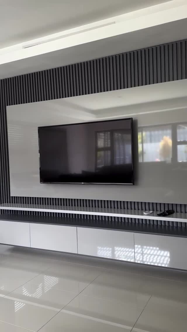 A modern media wall with a glossy white panel, dark wood slats, and a floating console.