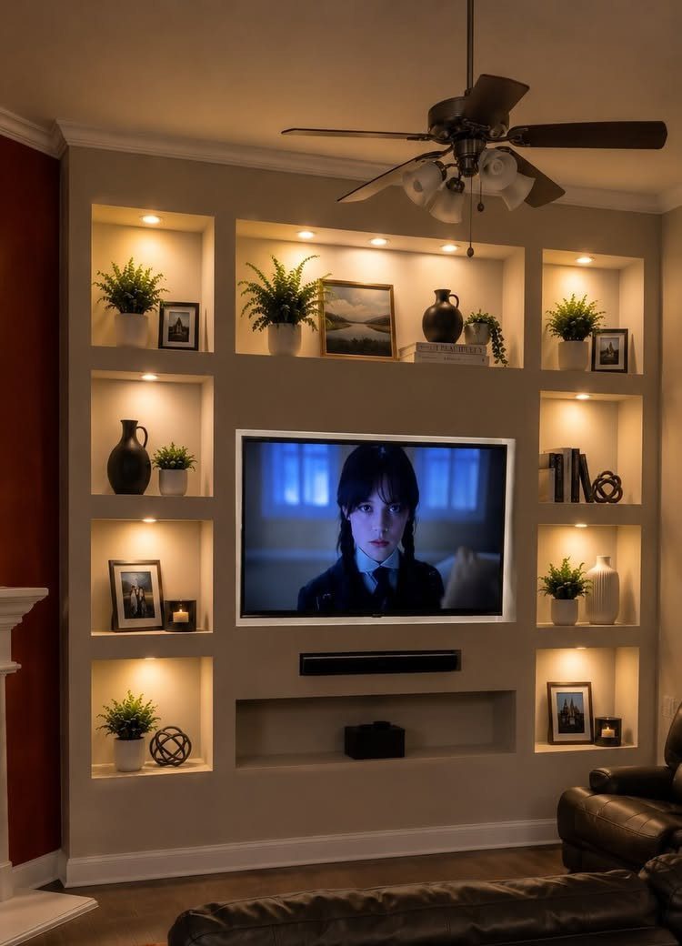 A built-in media wall with a recessed TV and several illuminated decorative cubby holes.