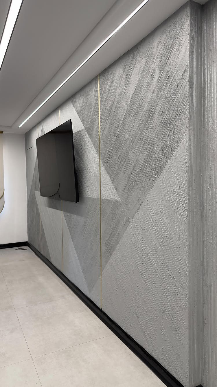 Grey textured wall with large geometric patterns and a mounted television in a modern room.