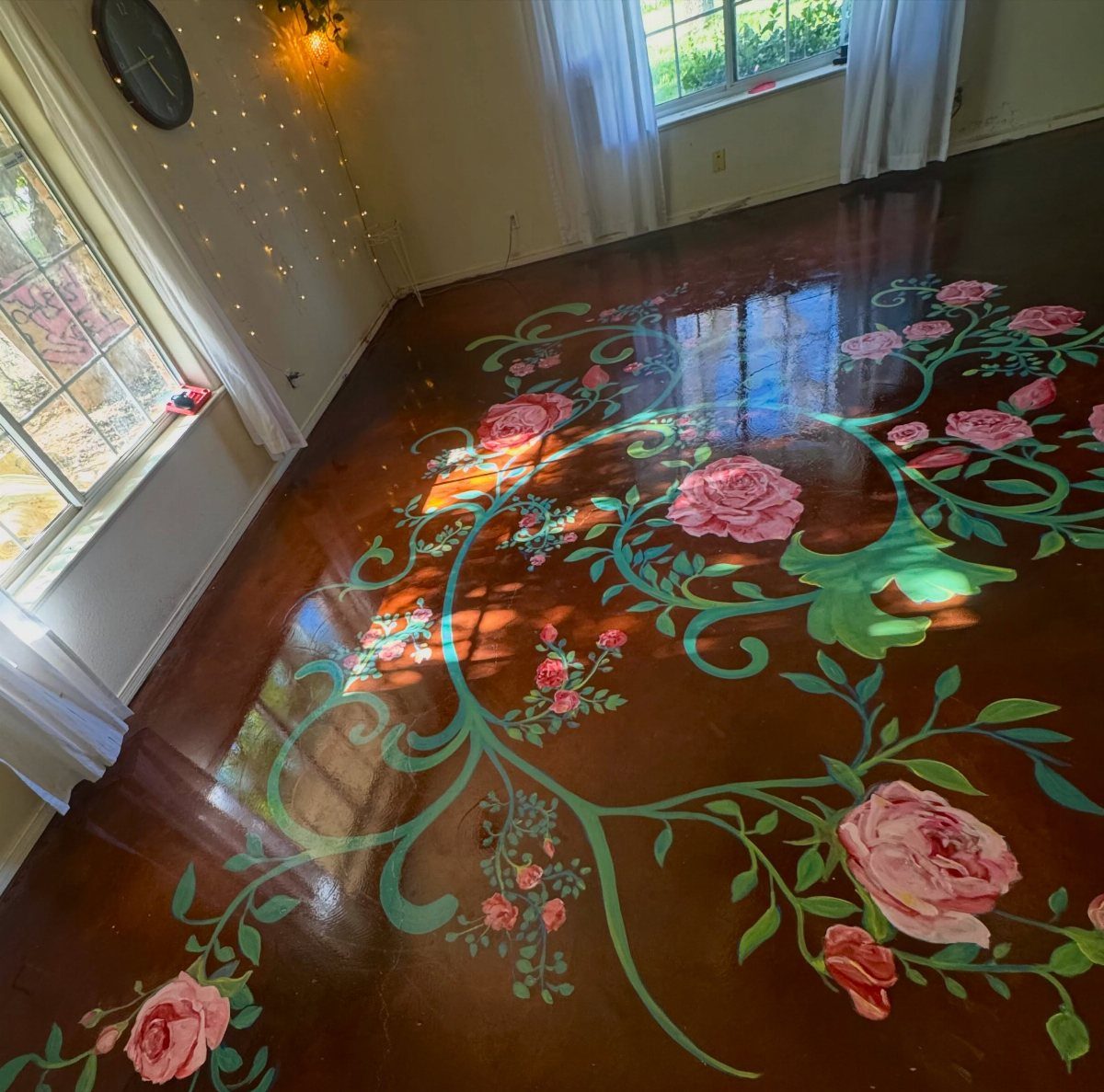 5 Painted Wood Floors for Pattern, Pale Color, and Bold Graphics 5 A dark wooden floor decorated with a large, glossy painted mural of pink roses and green vines.