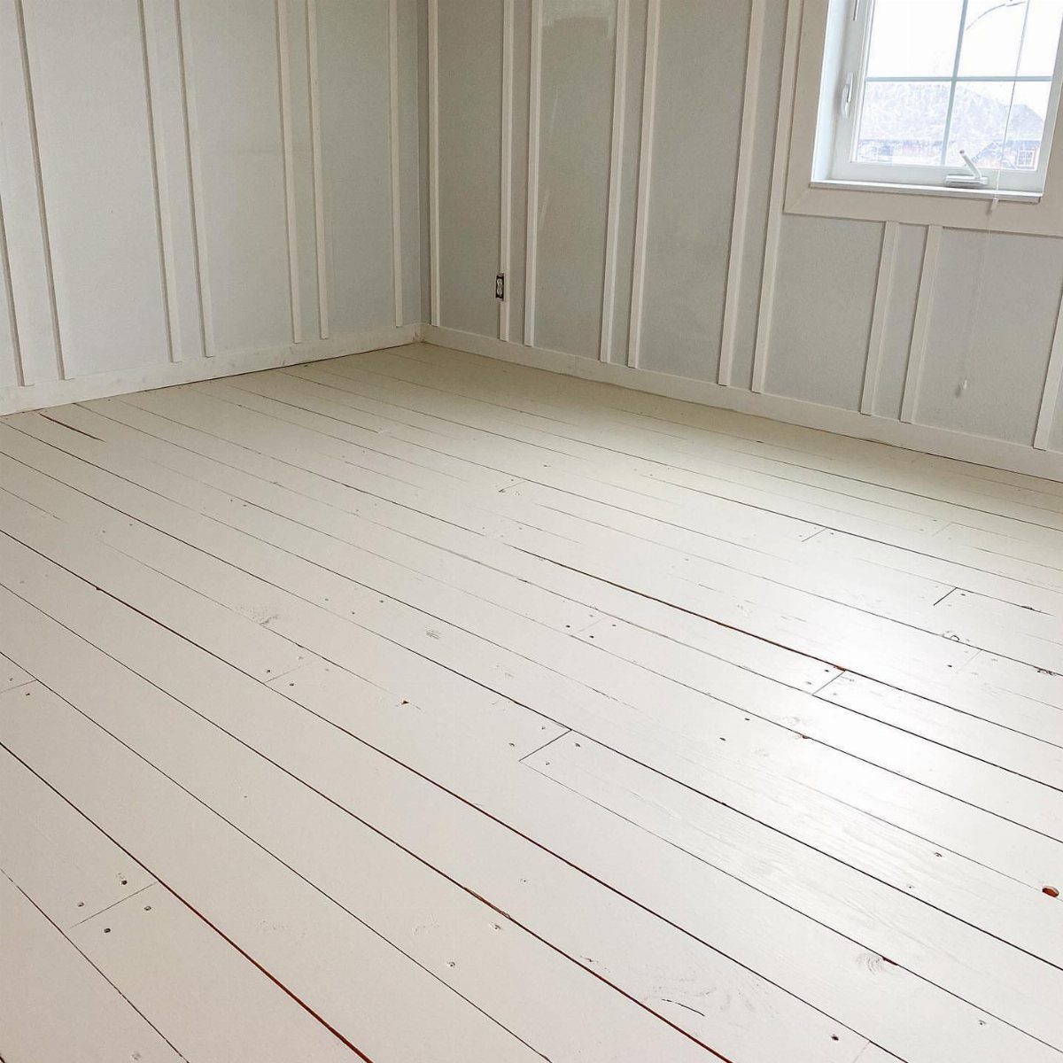 5 Painted Wood Floors for Pattern, Pale Color, and Bold Graphics 2 White painted wooden floorboards in a room with matching white paneled walls.