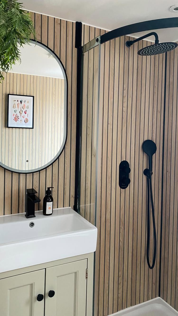 Vertical wood-look laminate panels installed in a modern bathroom with a white sink and black fixtures.
