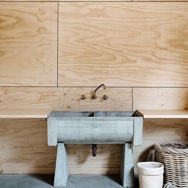 12 Plywood Wall Ideas for Living Rooms, Offices and Bedrooms 10 Plywood wall panels behind a rustic metal sink and a wicker basket on a concrete floor.