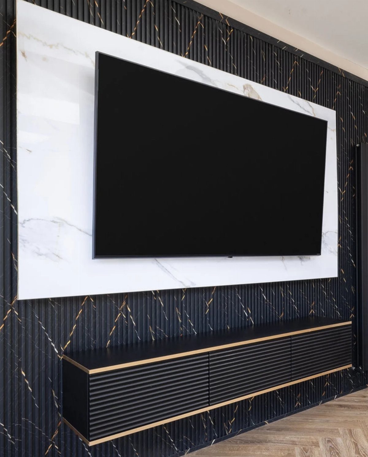 PVC Panel Design: 9 Ideas for Walls, Ceilings and Exteriors 5 Television mounted on a white marble panel against a dark ribbed wall with gold accents.