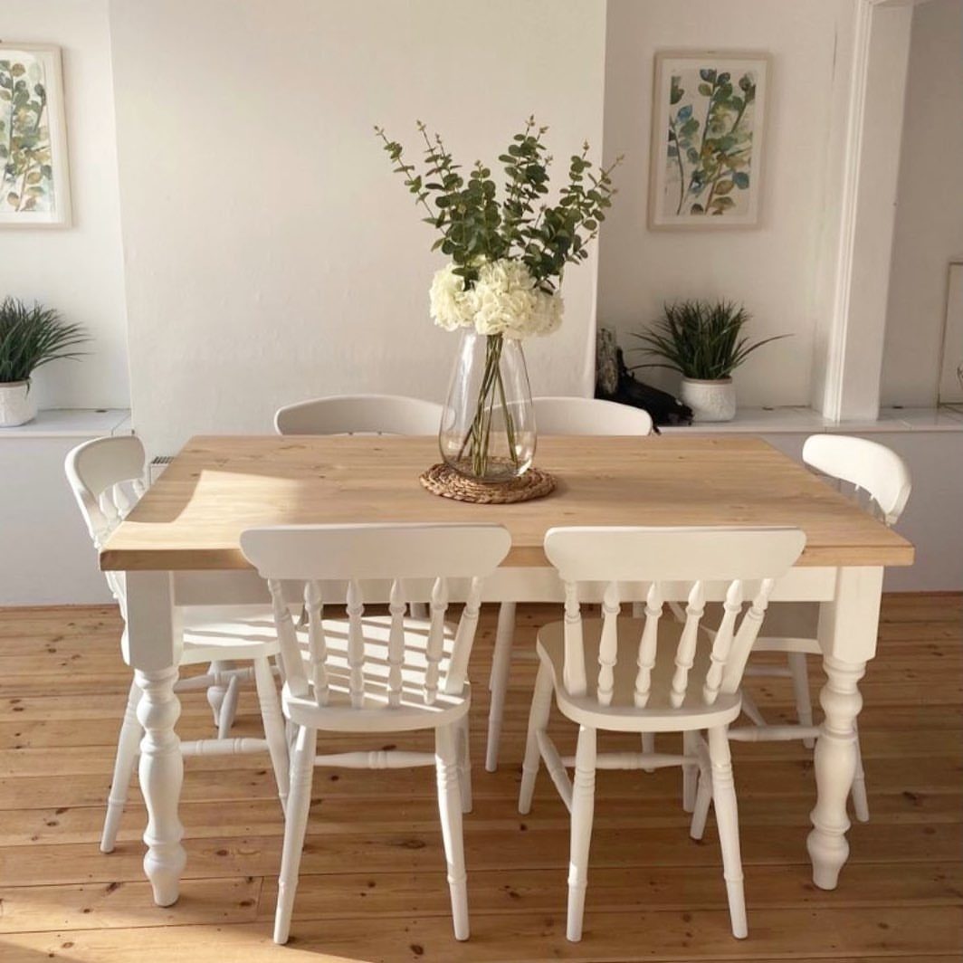 29 Rustic Farmhouse Kitchen Ideas That Feel Collected, Not Cataloged 20 A light wood dining table with white spindle-back chairs and a floral centerpiece.