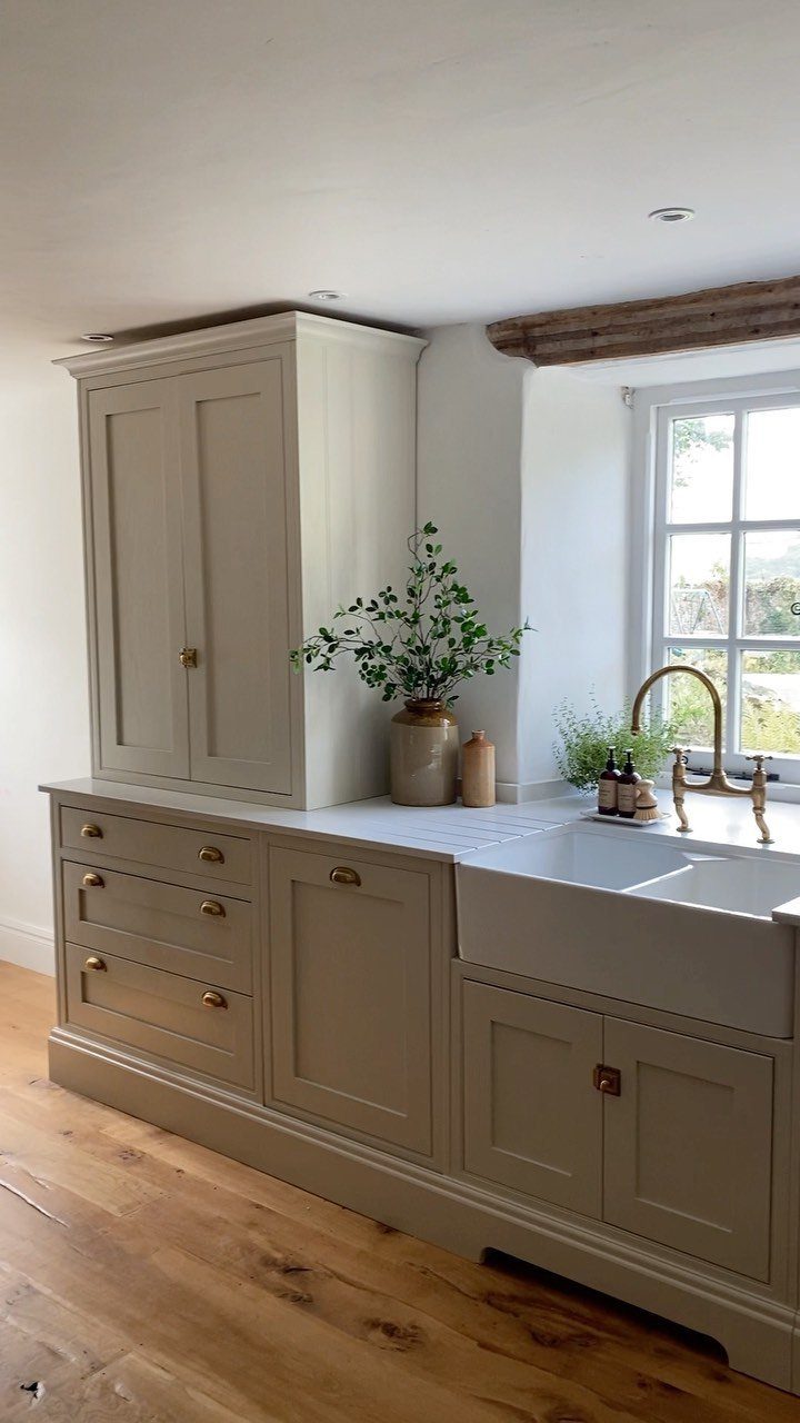 29 Rustic Farmhouse Kitchen Ideas That Feel Collected, Not Cataloged 11 Light wood plank flooring in a kitchen with beige cabinetry and a white farmhouse sink.