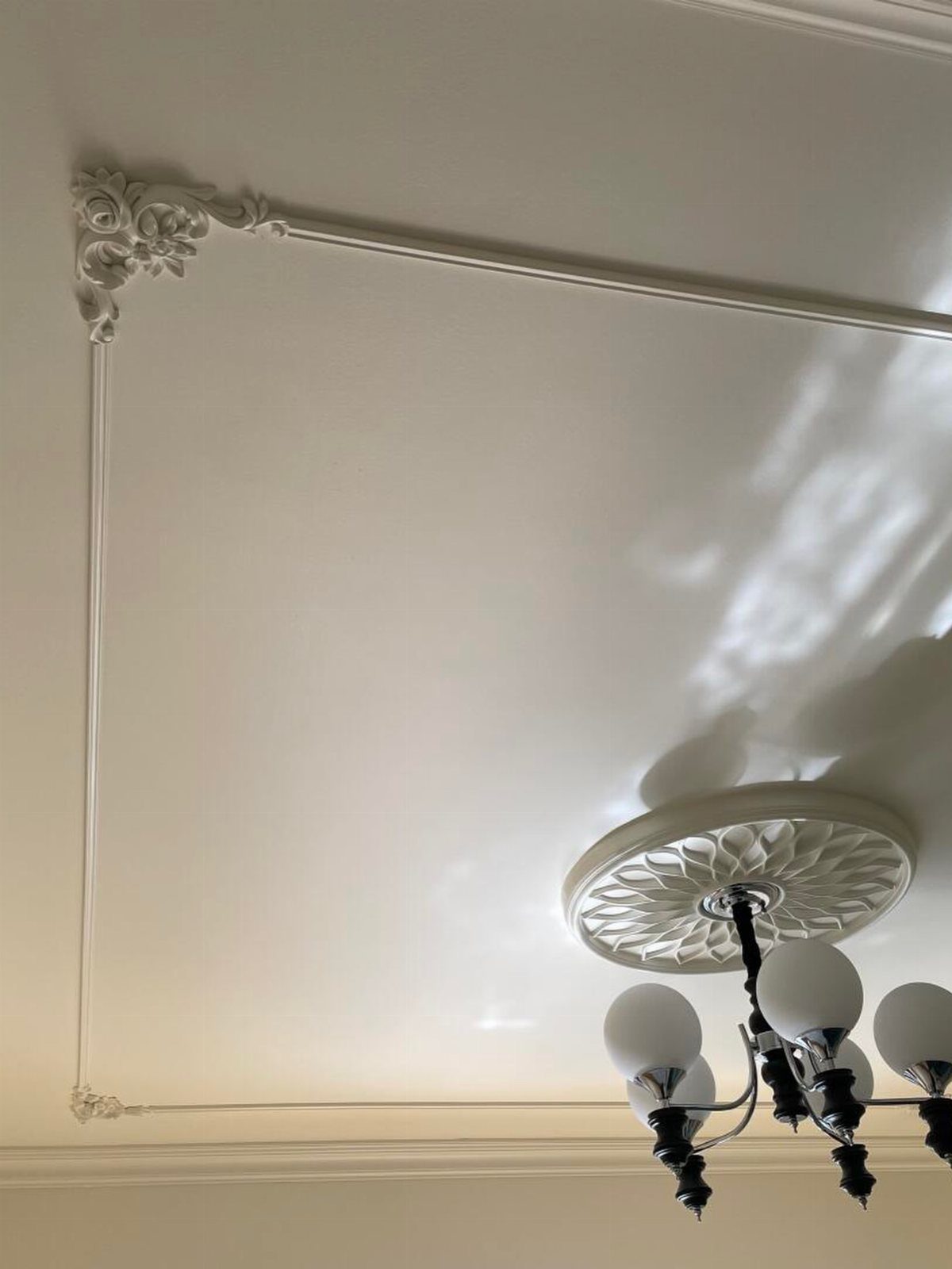 Ornate white crown moulding and a decorative ceiling medallion on a white ceiling.