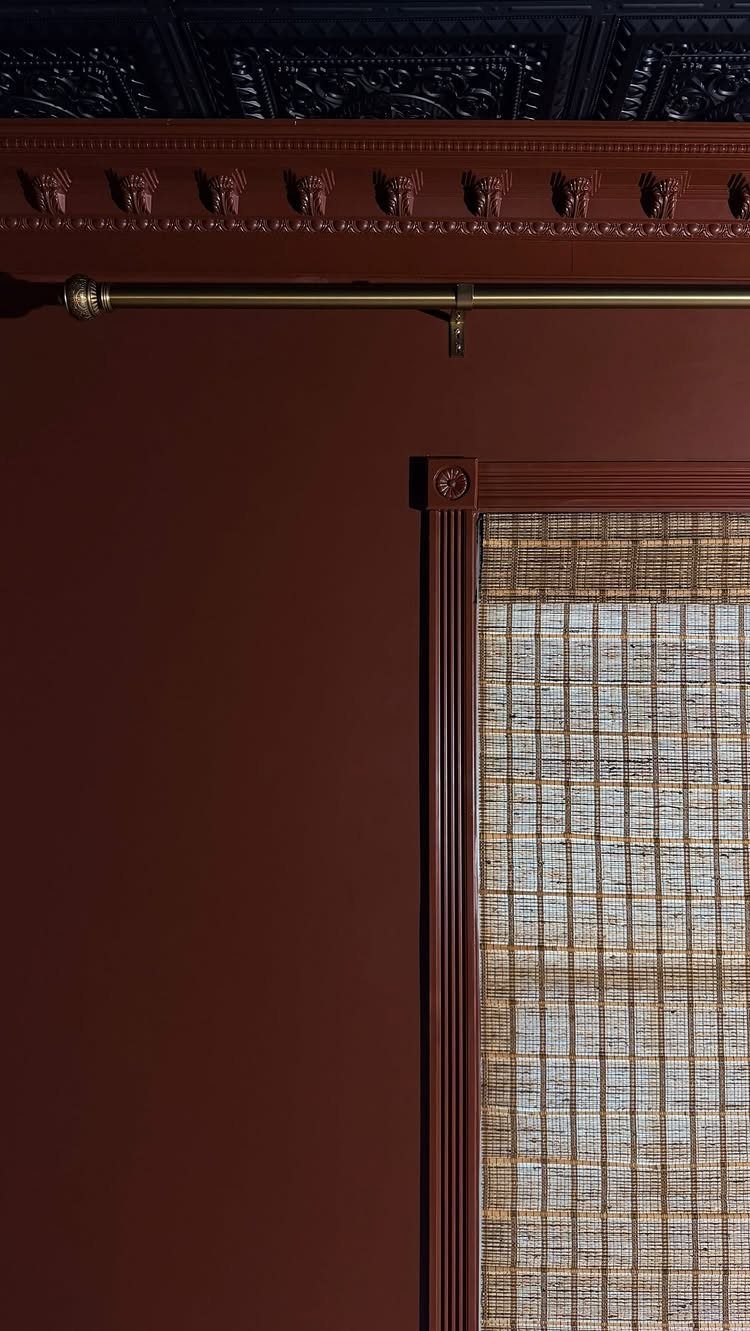 Decorative reddish-brown crown moulding installed at the junction of a dark wall and ceiling.