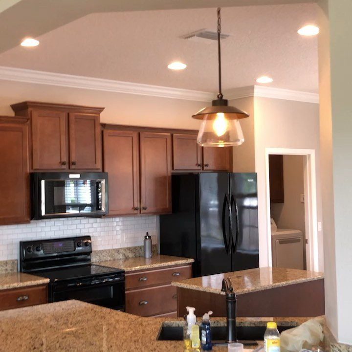 Trim Work on Walls: 8 Styles That Add Detail to Any Room 8 Kitchen with brown cabinets, black appliances, granite counters, and white crown molding trim on the ceiling.