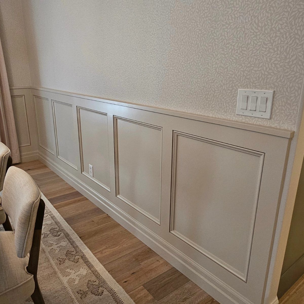 Trim Work on Walls: 8 Styles That Add Detail to Any Room 1 Decorative wainscoting with rectangular panel molding installed on a light-colored interior wall.