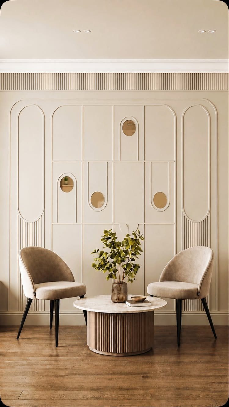 Cream geometric wall paneling behind two beige chairs and a marble coffee table.