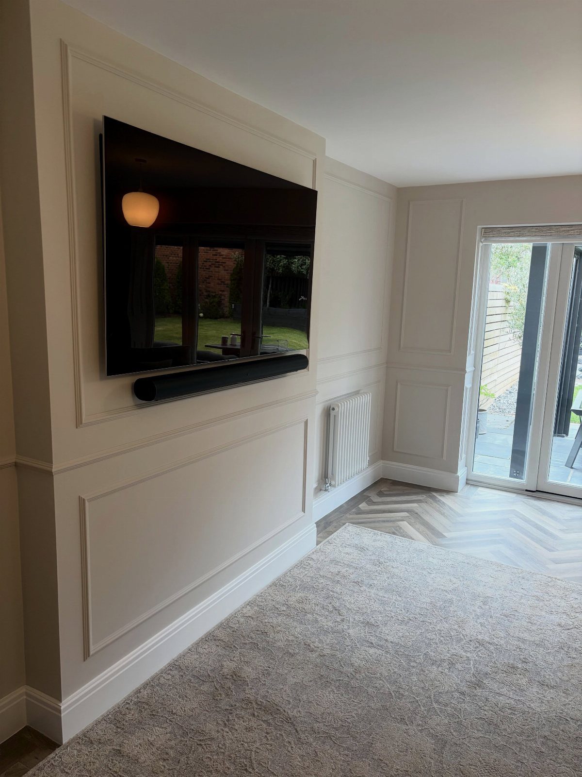 White wainscoting panels on a living room wall with a mounted television and soundbar.