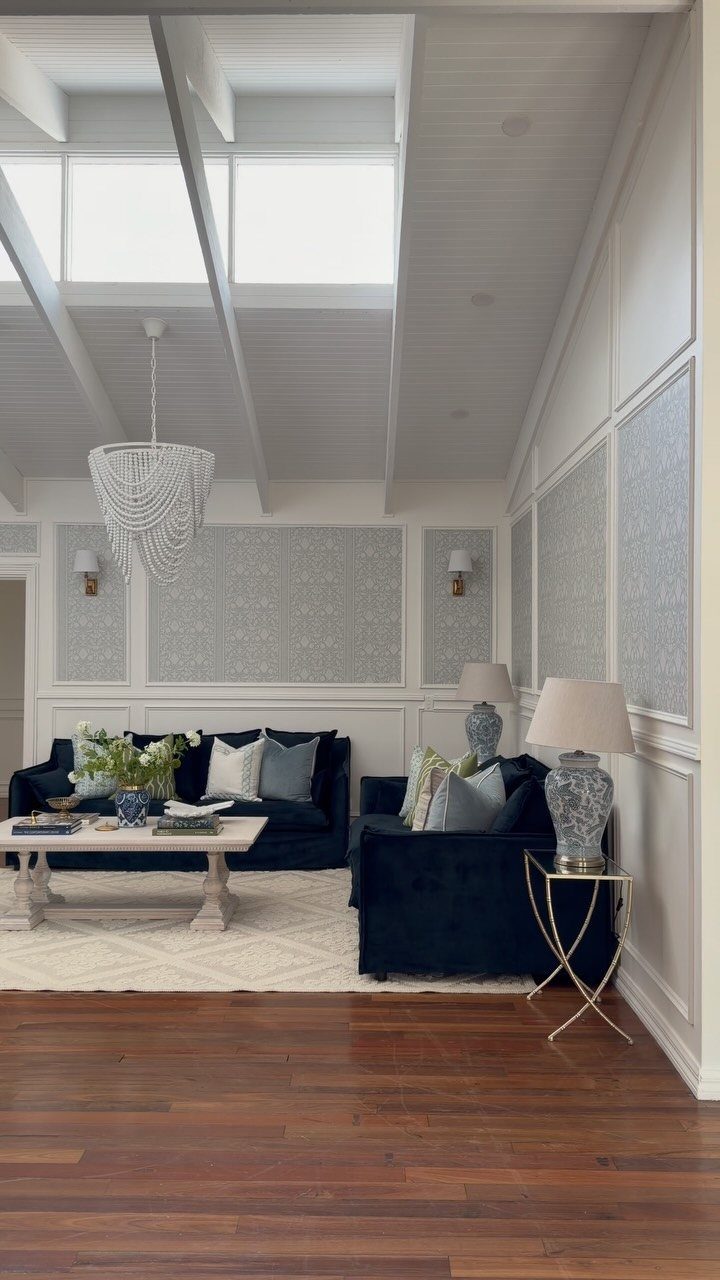 White wainscoting with patterned wallpaper inset in a bright, modern living room.