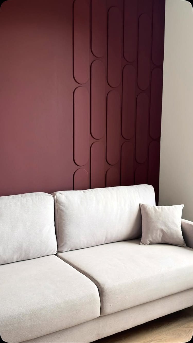 23 Wall Decor Design Ideas (Gallery Walls, Moss Walls, Rattan) 12 A burgundy wall with raised geometric pill shapes behind a light beige sofa.
