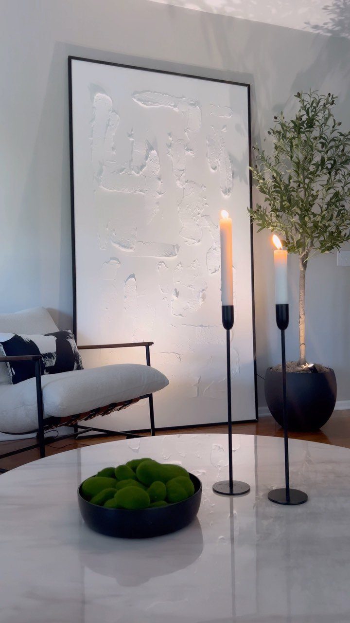 23 Wall Decor Design Ideas (Gallery Walls, Moss Walls, Rattan) 7 Large white textured artwork in a black frame leaning against a grey wall in a living room.