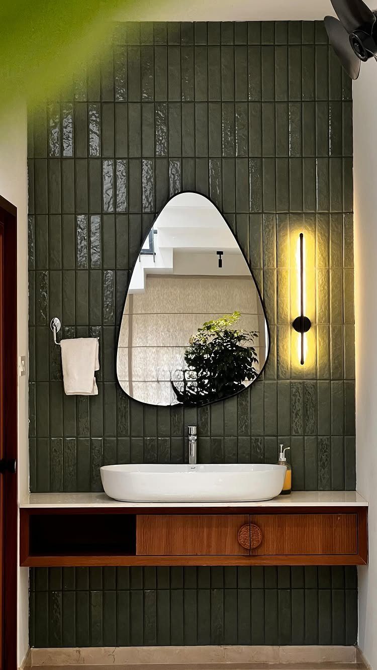 23 Wall Decor Design Ideas (Gallery Walls, Moss Walls, Rattan) 21 Dark green textured tiles on a bathroom wall with an organic mirror and white sink.