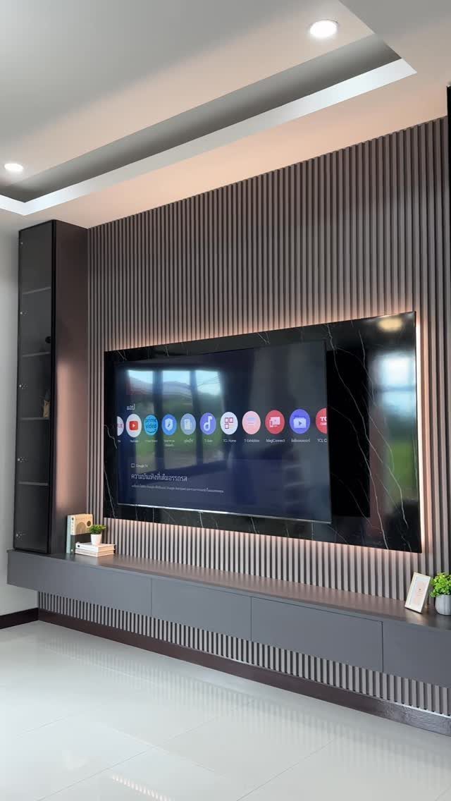 Vertical grey fluted wall panels with a large television and a long floating media console.